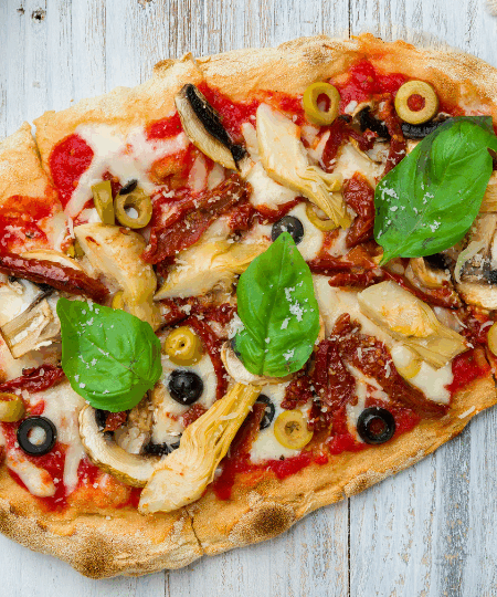 Mediterrane Vegane Pizza mit Oliven, Artischocken und Basilikum