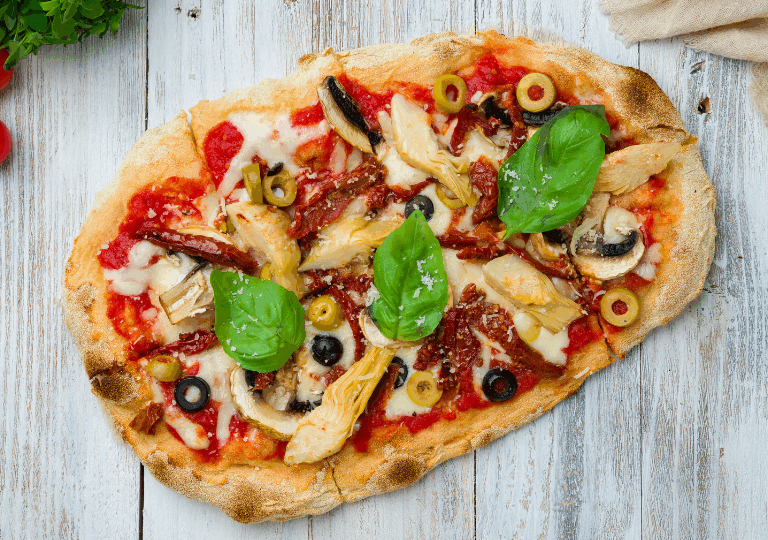 Mediterrane Vegane Pizza mit Oliven, Artischocken und Basilikum