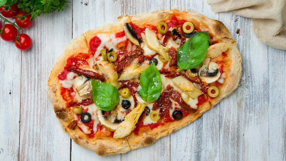 Mediterrane Vegane Pizza mit Oliven, Artischocken und Basilikum